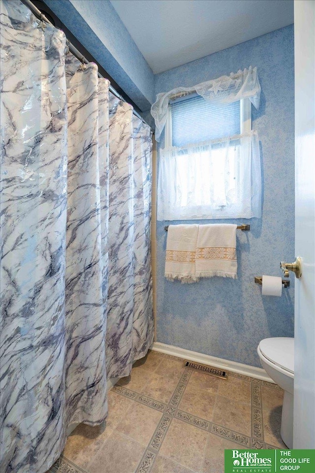 bathroom with toilet, a shower with shower curtain, tile patterned flooring, and baseboards