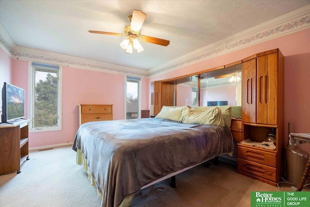 bedroom with ornamental molding, visible vents, a ceiling fan, and light colored carpet