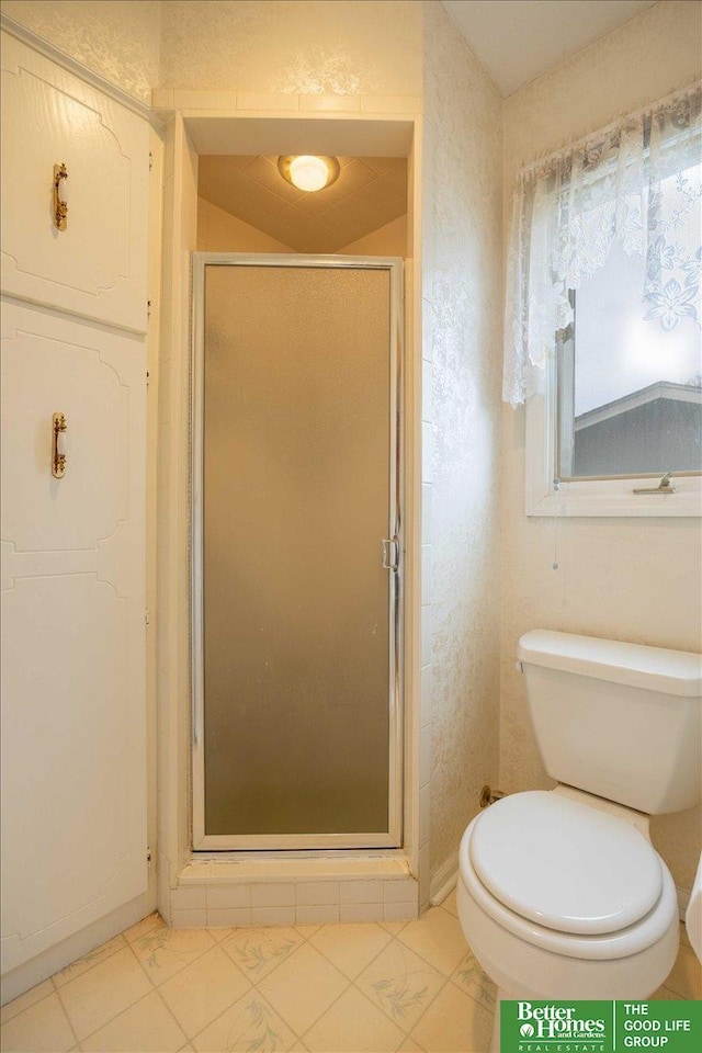 full bath featuring a shower stall, tile patterned flooring, baseboards, and toilet