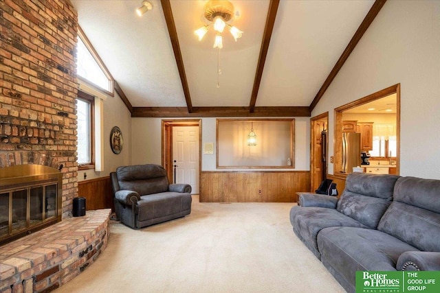 living area with a fireplace, wooden walls, carpet floors, beamed ceiling, and a wainscoted wall