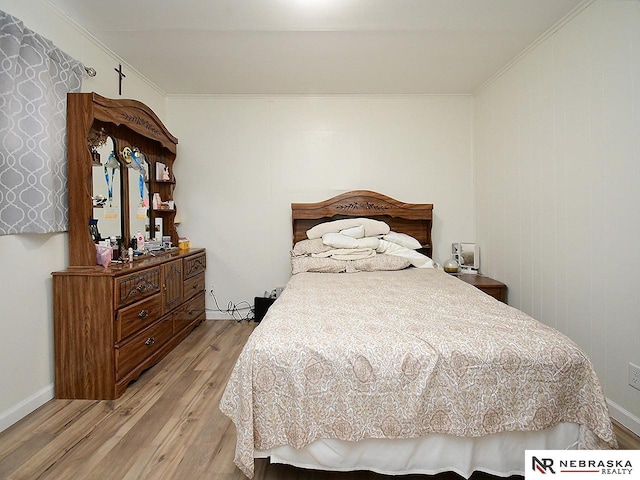 bedroom with crown molding, baseboards, and light wood-type flooring