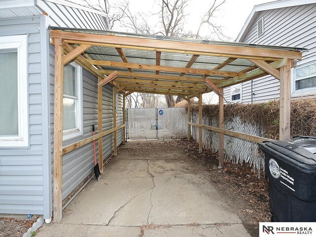 view of car parking with an attached carport and fence