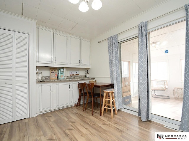 kitchen featuring white cabinets, crown molding, and light wood-style floors