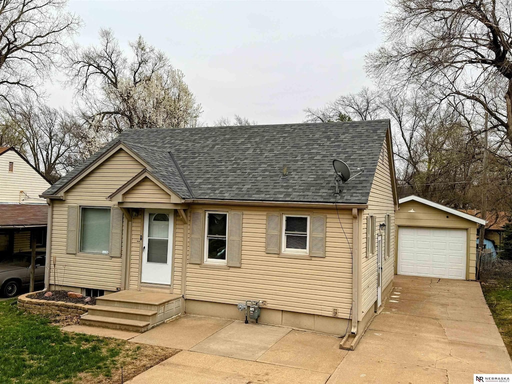 bungalow-style house featuring roof with shingles, a garage, an outdoor structure, and driveway
