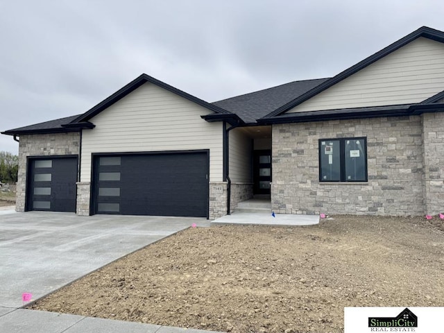modern home with concrete driveway, an attached garage, stone siding, and a shingled roof
