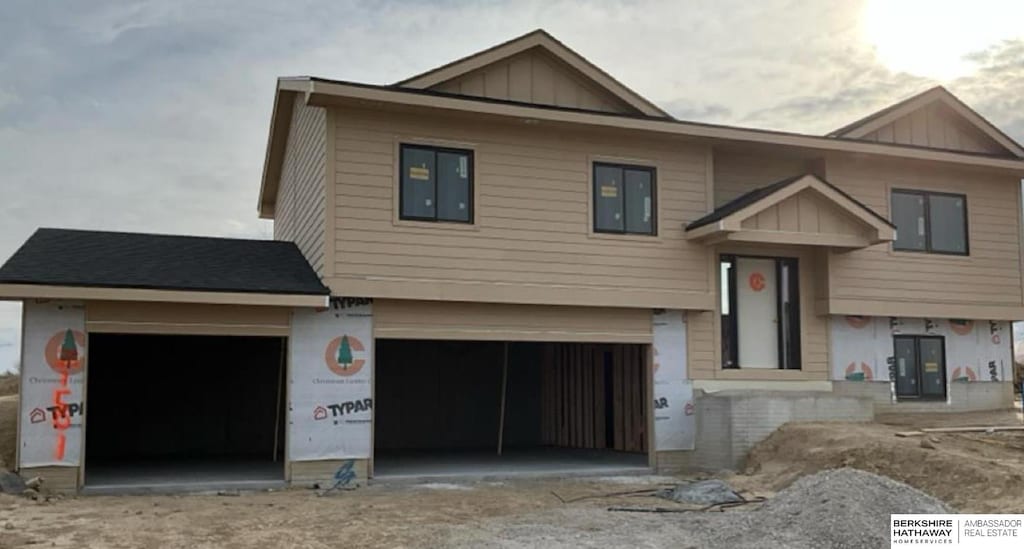 split foyer home with board and batten siding, an attached garage, and driveway