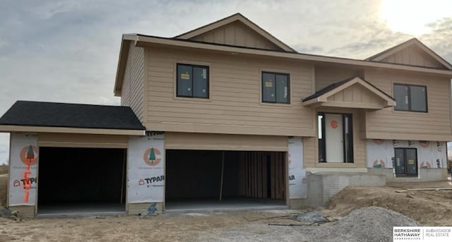 split foyer home with board and batten siding, an attached garage, and driveway
