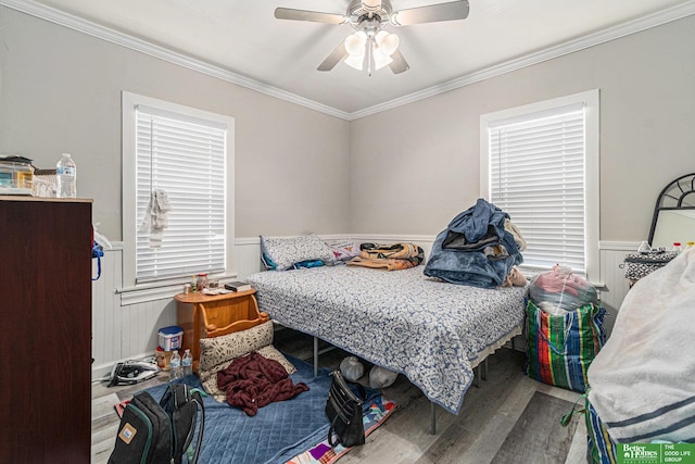 bedroom featuring wainscoting, a ceiling fan, wood finished floors, and crown molding