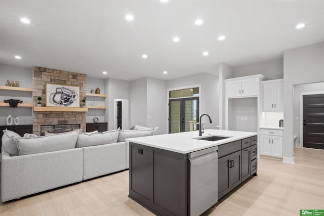 kitchen with a fireplace, open floor plan, white cabinets, dishwasher, and a sink