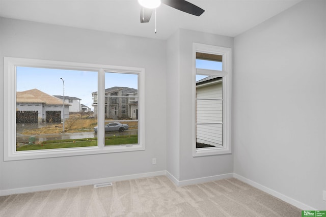 spare room featuring visible vents, baseboards, a ceiling fan, and carpet