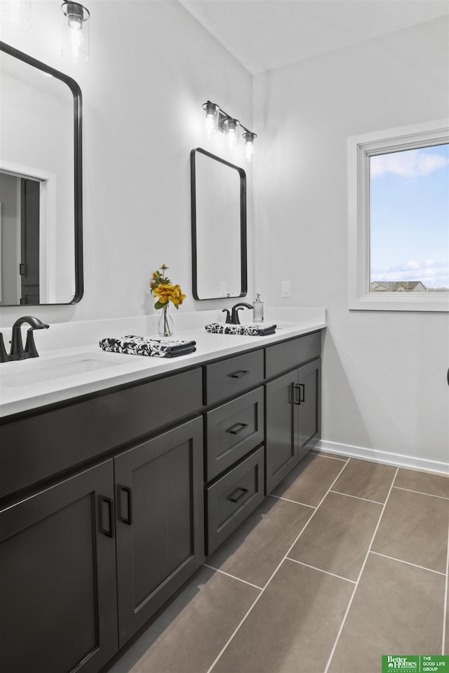 bathroom featuring tile patterned flooring, double vanity, baseboards, and a sink