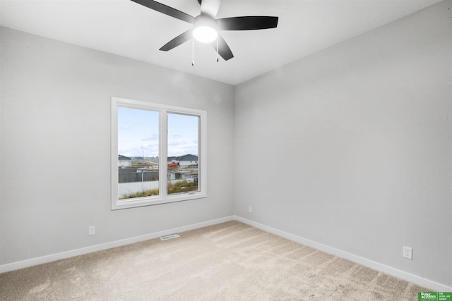 spare room with visible vents, light colored carpet, baseboards, and ceiling fan