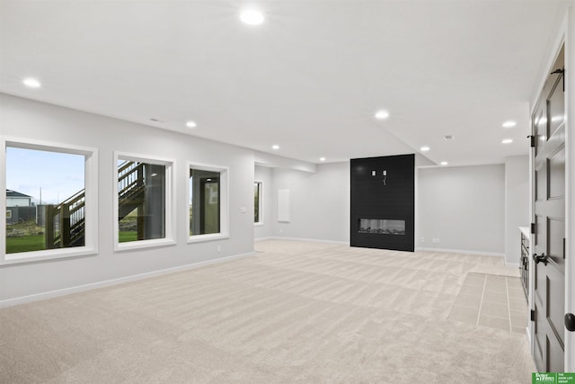 spare room with light colored carpet, a fireplace, baseboards, and recessed lighting