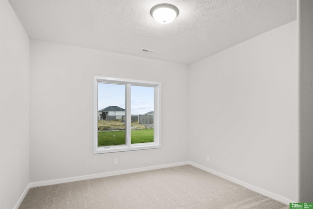 unfurnished room with a textured ceiling, carpet flooring, baseboards, and visible vents