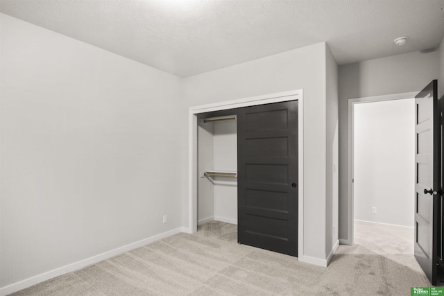 unfurnished bedroom with a closet, carpet flooring, baseboards, and a textured ceiling