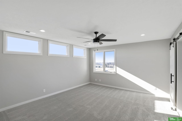 empty room with visible vents, a barn door, ceiling fan, recessed lighting, and light carpet