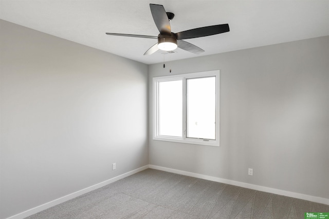 carpeted spare room featuring baseboards and ceiling fan