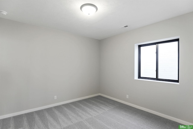carpeted spare room featuring visible vents and baseboards