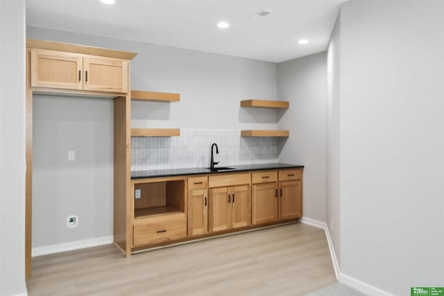 kitchen with light wood-type flooring, a sink, and open shelves