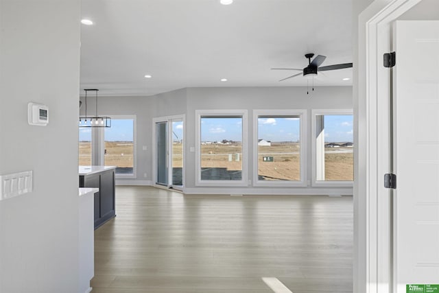 unfurnished living room with baseboards, a ceiling fan, wood finished floors, and recessed lighting