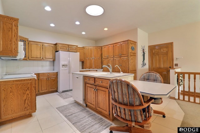 kitchen featuring a center island with sink, light countertops, white appliances, and backsplash
