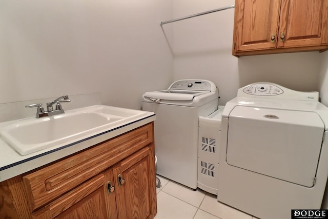 laundry area with light tile patterned flooring, washing machine and dryer, a sink, and cabinet space
