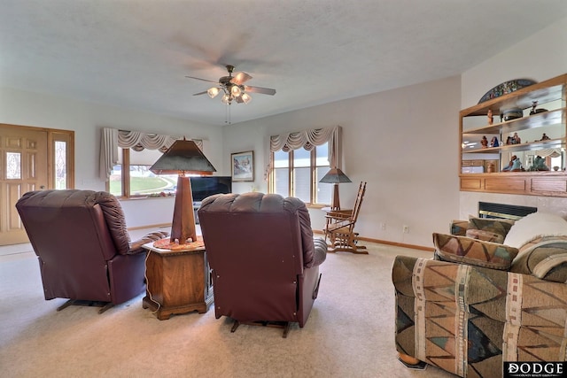 living room with light colored carpet, ceiling fan, a fireplace, and baseboards