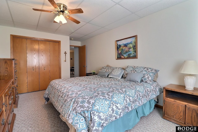 carpeted bedroom with a paneled ceiling, a closet, and ceiling fan