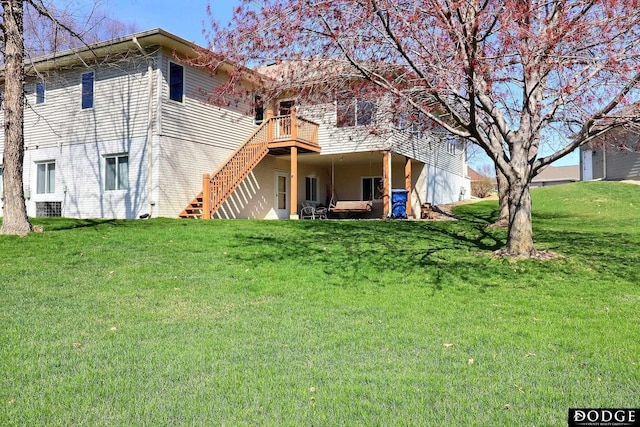 rear view of property with a lawn, a deck, and stairs