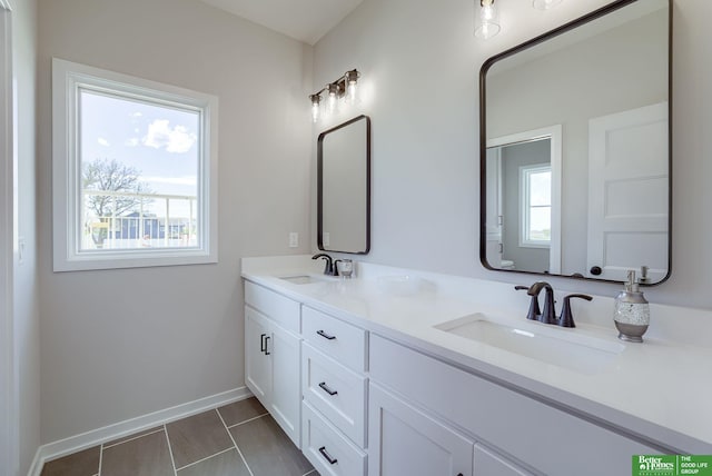 bathroom with a sink, tile patterned floors, double vanity, and baseboards