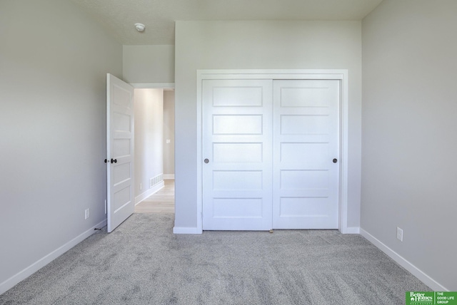 unfurnished bedroom featuring carpet floors, baseboards, and a closet