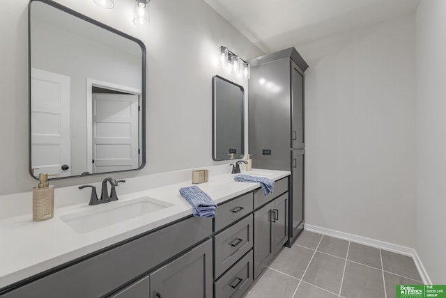 bathroom with a sink, tile patterned floors, double vanity, and baseboards
