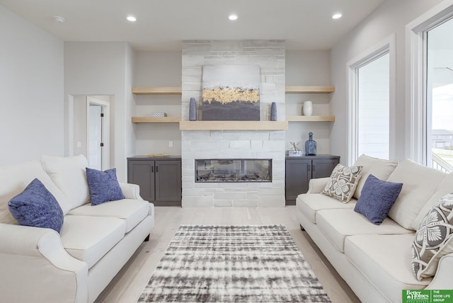living area featuring light wood-style flooring, a large fireplace, and recessed lighting