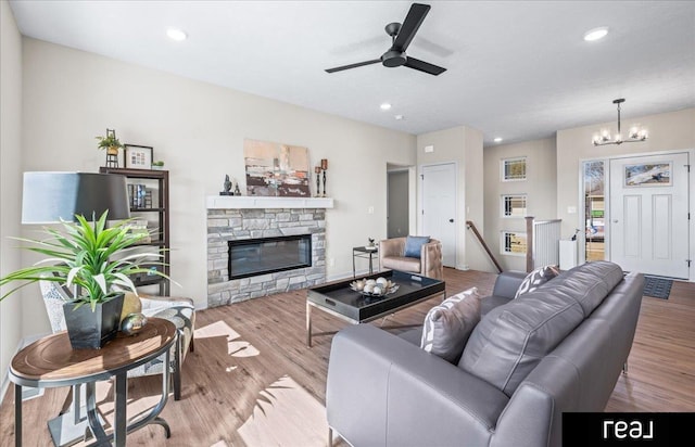 living area featuring ceiling fan with notable chandelier, recessed lighting, wood finished floors, and a fireplace