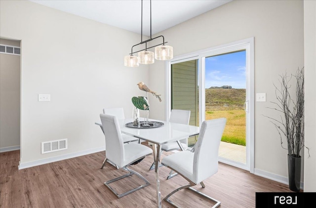 dining room featuring visible vents, baseboards, and wood finished floors