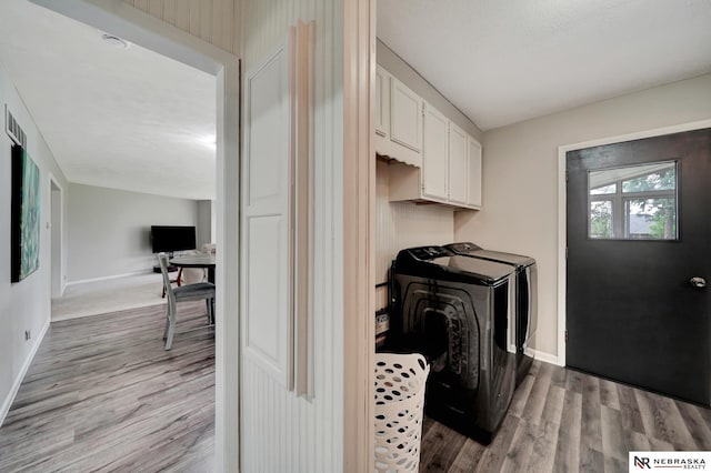 laundry area with baseboards, washing machine and dryer, light wood finished floors, and cabinet space
