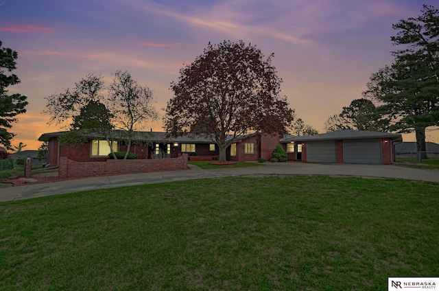 view of front of house with a detached garage, brick siding, driveway, and a front yard