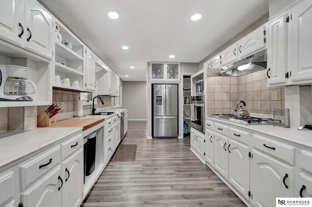 kitchen featuring backsplash, open shelves, a sink, under cabinet range hood, and stainless steel appliances