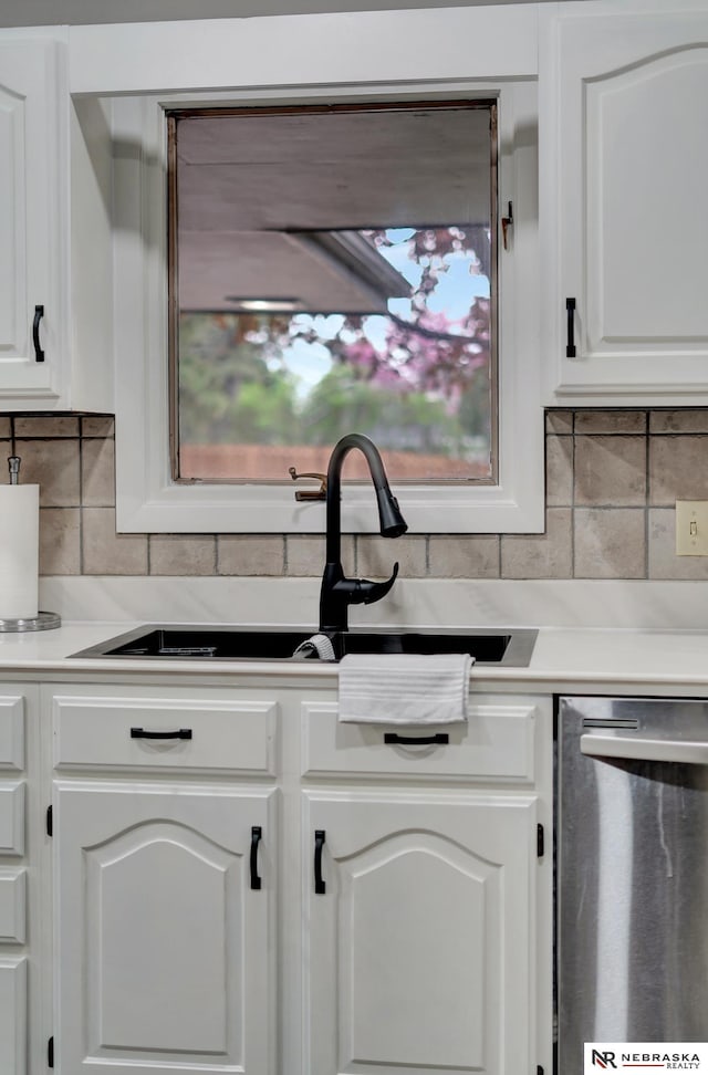 kitchen featuring a sink, white cabinets, stainless steel dishwasher, and backsplash