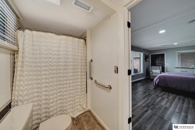 ensuite bathroom featuring toilet, baseboards, visible vents, and wood finished floors