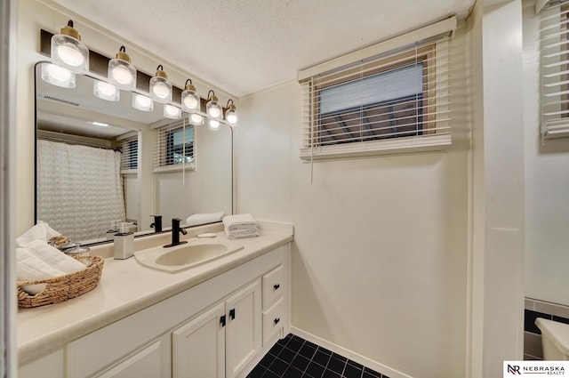 bathroom with vanity, a textured ceiling, tile patterned floors, baseboards, and visible vents