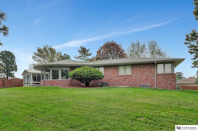 exterior space featuring a yard, brick siding, and a sunroom