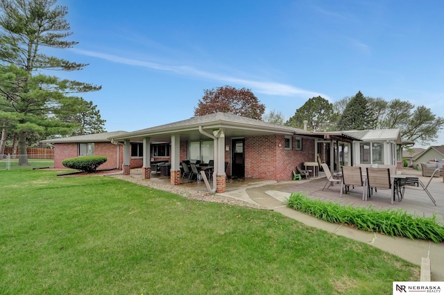 rear view of house featuring a yard, a patio area, and brick siding