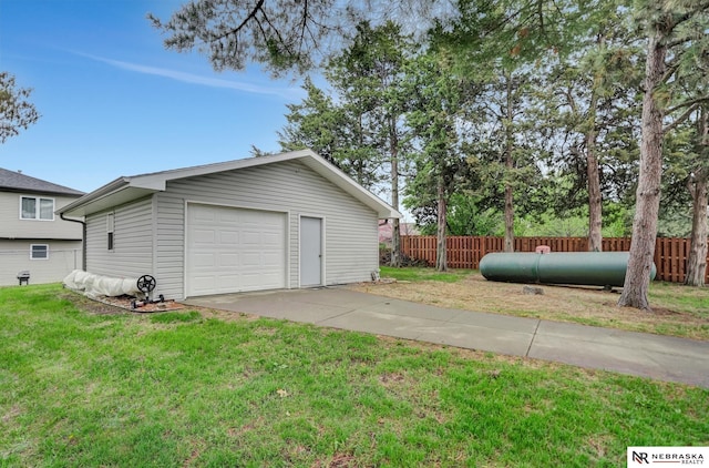 detached garage featuring fence and concrete driveway