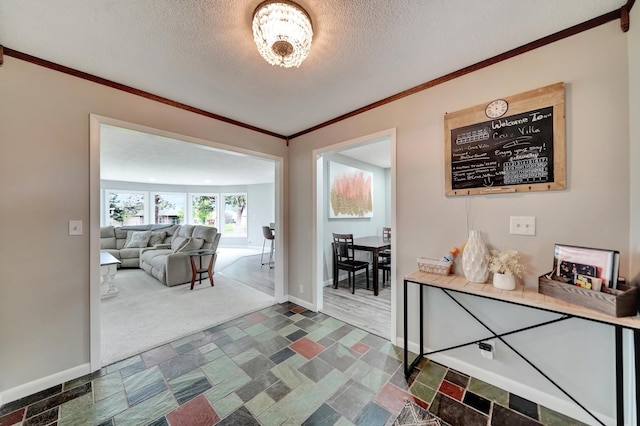 corridor featuring baseboards, ornamental molding, stone finish flooring, and a textured ceiling