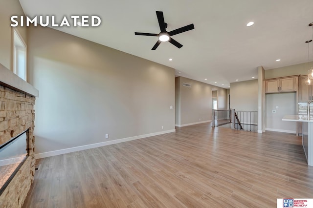 10551 Majestic Ln, Lincoln, NE 68527 - unfurnished living room featuring light wood-style flooring, a stone fireplace, a ceiling fan, and visible vents