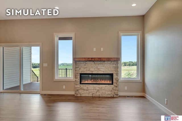 10551 Majestic Ln, Lincoln, NE 68527 - unfurnished living room featuring wood finished floors, baseboards, a stone fireplace, and plenty of natural light