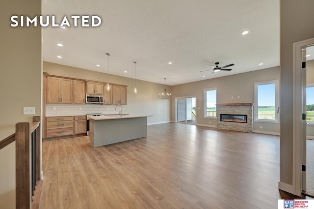 10551 Majestic Ln, Lincoln, NE 68527 - kitchen with a stone fireplace, light wood finished floors, ceiling fan with notable chandelier, decorative backsplash, and stainless steel appliances