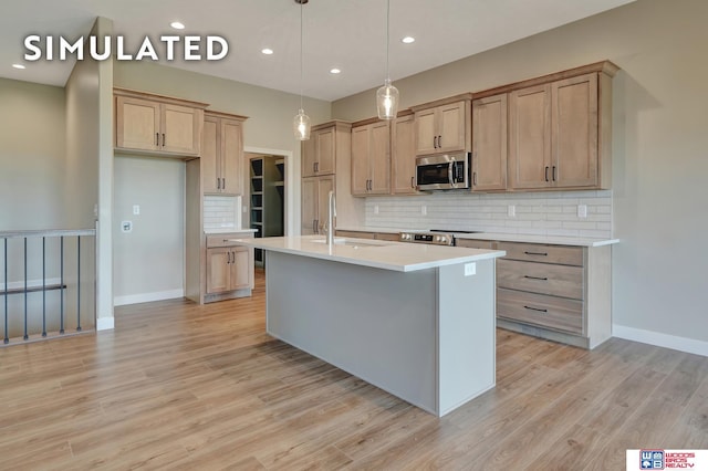 10551 Majestic Ln, Lincoln, NE 68527 - kitchen with an island with sink, light countertops, stainless steel appliances, light wood finished floors, and a sink