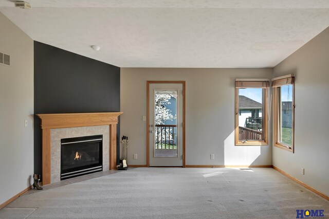 unfurnished living room featuring carpet flooring, visible vents, baseboards, and a healthy amount of sunlight